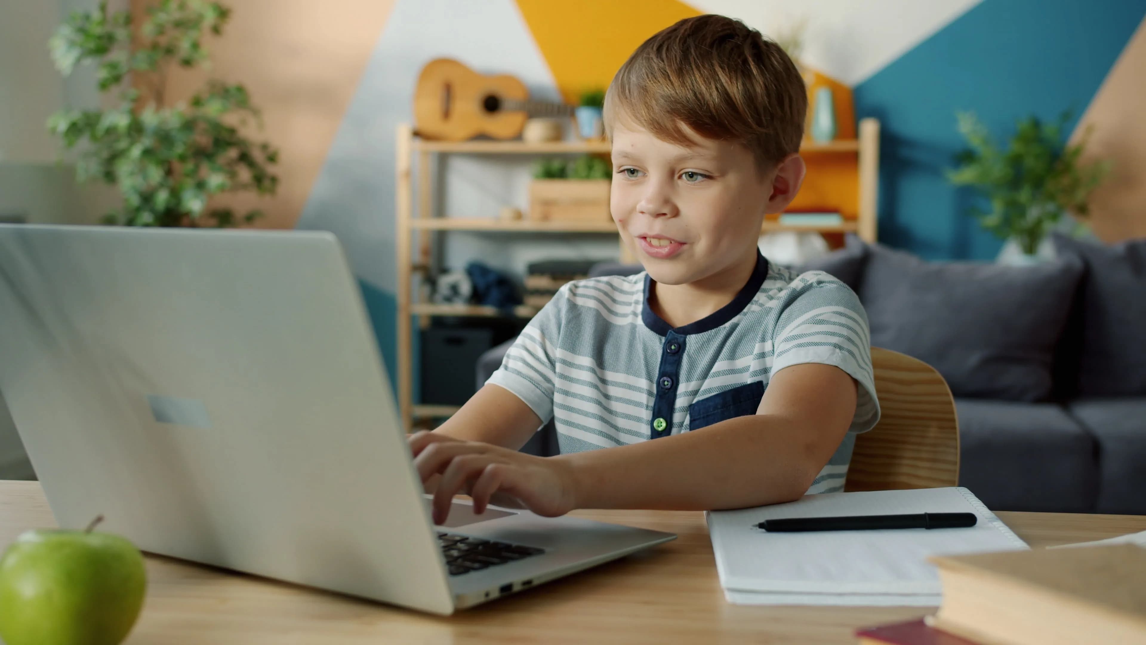 Uczeń pracuje przy laptopie i zapisuje rozwiązanie w zeszycie